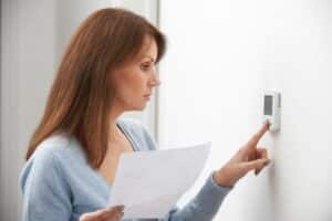 Woman Adjusting Thermostat In Recovery Mode