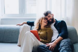 Happy Couple Relaxing Together On A Couch In A Bright Comfortable Home