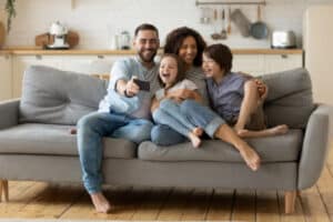 Smiling Parents With Little Kids Laughing Using Smartphone Together.